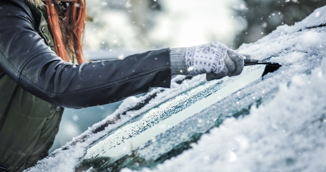 Woman scraping ice of a windscreen